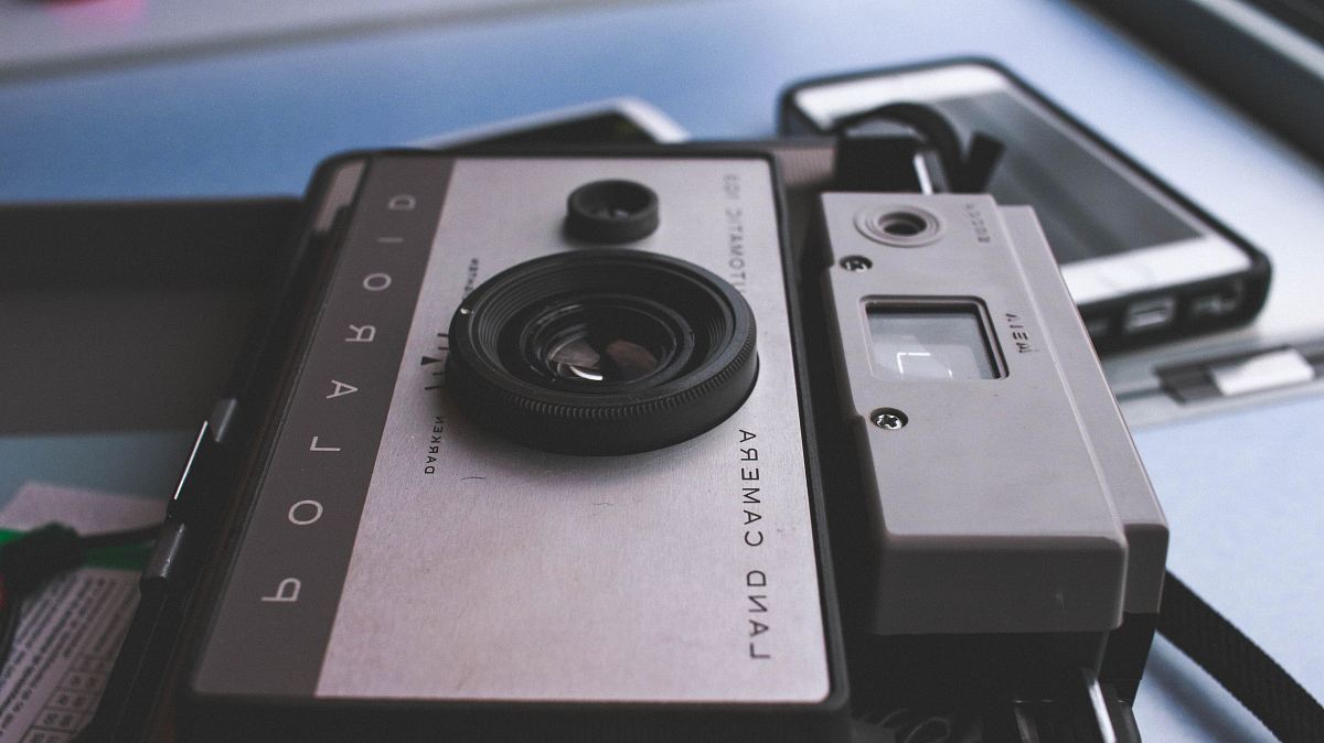 gray Polaroid land camera on table near white Android smartphone